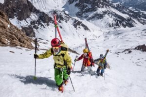 Sci alpinisti che salgono un canale con gli sci negli zaini